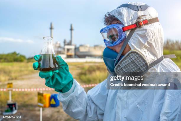 a toxicology specialist in a white lab coat looks at the tube after the test. - contaminación de aguas fotografías e imágenes de stock