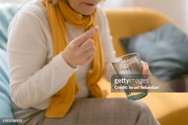 close up view of an unrecognizable mature woman taking a pill. - adults and pills stock-fotos und bilder