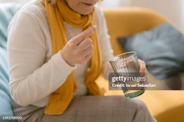 close up view of an unrecognizable mature woman taking a pill. - prendre des cachets photos et images de collection