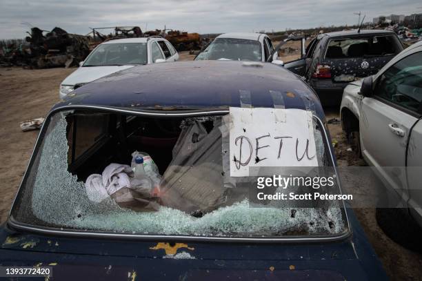 Car with a sign saying children and its glass shot with bullet holes lies among rusting remnants of a Russian armored column destroyed by Ukrainian...