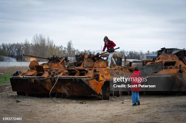 Television news team walks among the rusting remnants of a Russian armored column destroyed by Ukrainian forces are piled up on the outskirts of...