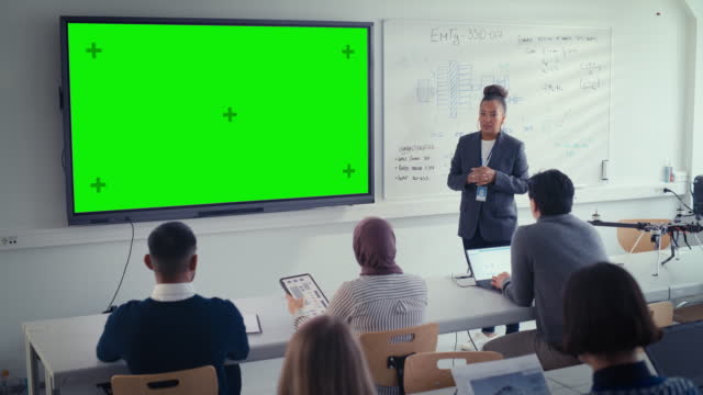 Black Female Teacher Explains Lesson to Students, Uses Green Screen Digital Whiteboard. Successful Woman Talks about Design. Science and Education Concept