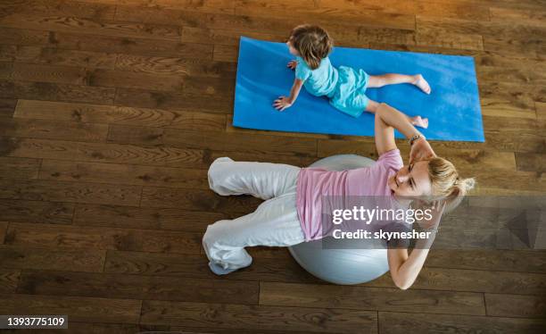 obige ansicht von alleinerziehender mutter und sohn, die zu hause auf dem boden trainieren. - exercise room stock-fotos und bilder