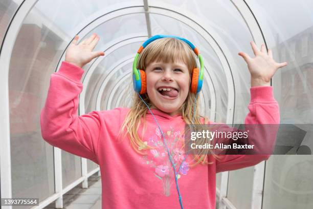 girl (6-7 years old) smiling with headphones in tunnel - bud fotografías e imágenes de stock