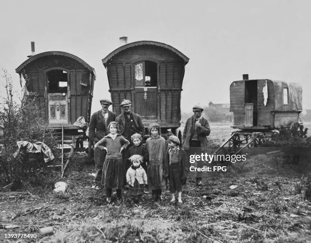 Roma people standing with their caravans beyond on Epsom Downs in Surrey, England, circa 1935. These Roma children are among the many visitors to...