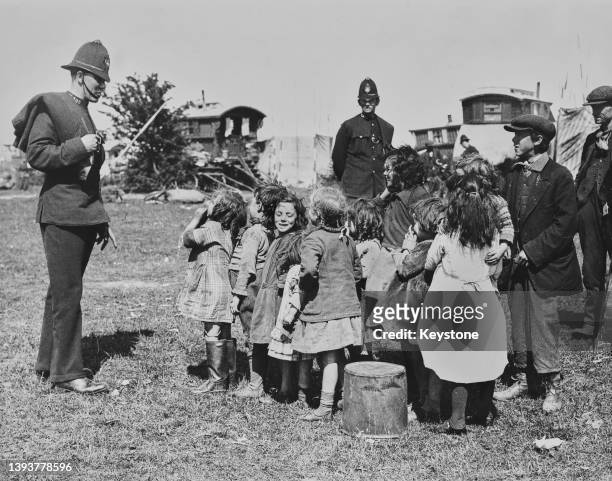 Policeman in conversation with a group of Roma children on Epsom Downs in Surrey, England, circa 1935. These Roma children are among the many...