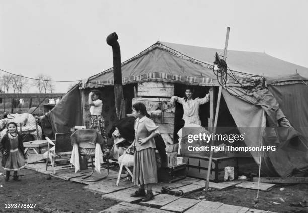 Roma children at their makeshift home, with furniture placed on what passes for a veranda, and a flue clearing the height of the property, on a Roma...