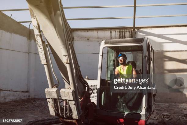 uomo che lavora con la terna in cantiere - benna meccanica foto e immagini stock