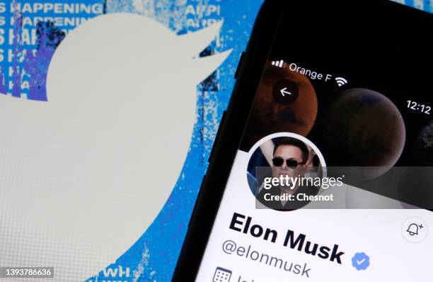 In this photo illustration, the Elon Musk’s Twitter account is displayed on the screen of an iPhone in front of the homepage of the Twitter website...