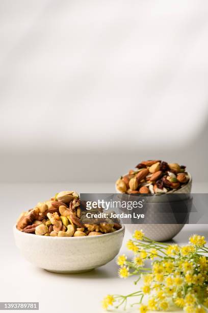 bowls with various nuts on a white table with white wall - pistachio stock pictures, royalty-free photos & images