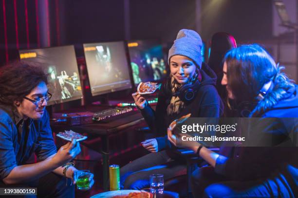 friends eating pizza while taking a break from playing video games - gamers stockfoto's en -beelden