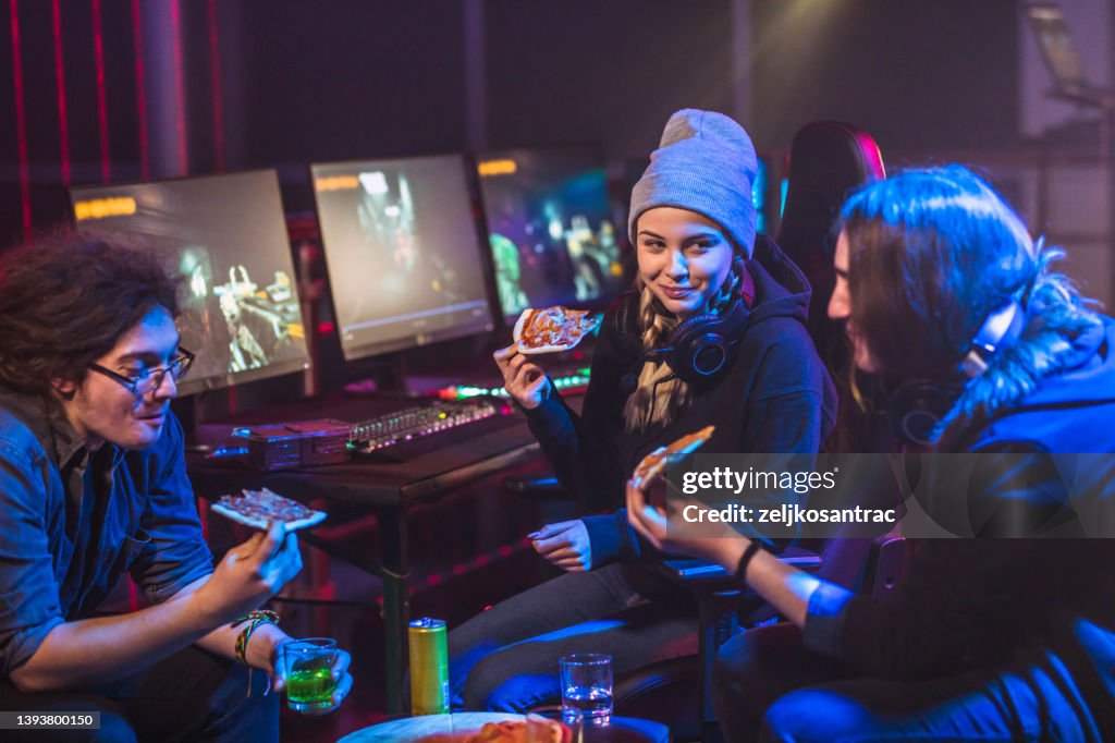 Friends eating pizza while taking a break from playing video games