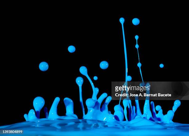 drops and splashes of blue paint in motion on a black background. - color explosion water stock-fotos und bilder