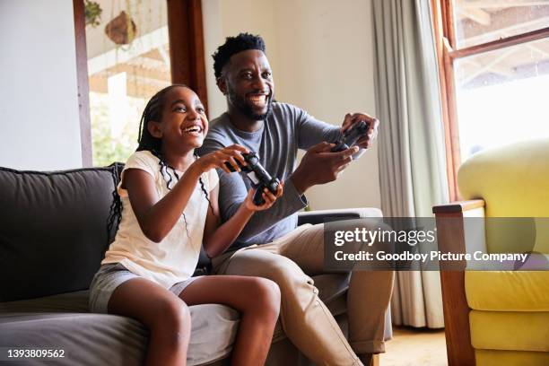 laughing girl and her dad playing video games together at home - gaming imagens e fotografias de stock