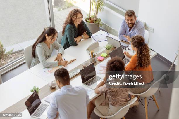 sie sind innovatoren des geschäfts - multi ethnic business people having discussion at table in board room stock-fotos und bilder