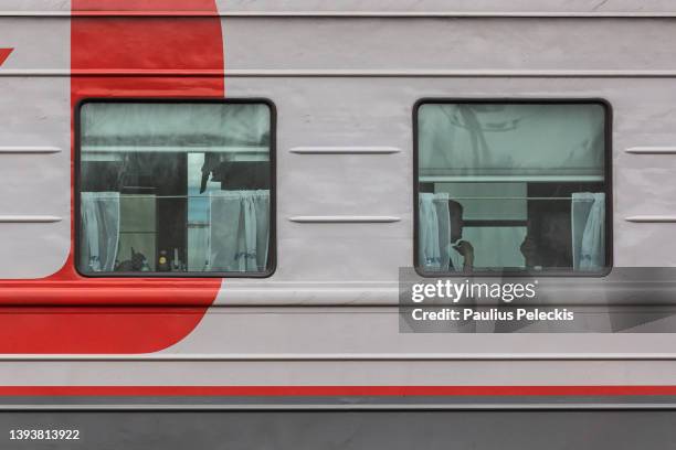 People on train reacts to photographs of Russia's war in Ukraine while they are displayed as part of an exhibition at the railway station where train...