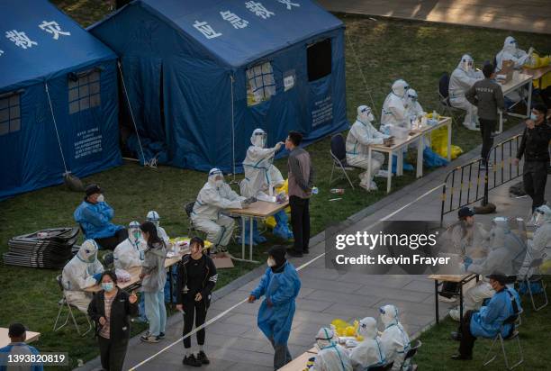 Health workers wear protective suits as employees from local high tech companies are given a nucleic acid tests to detect COVID-19 at a makeshift...