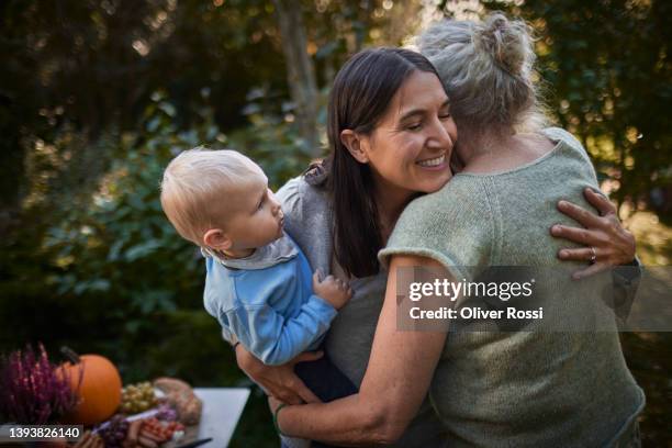 happy woman with baby boy hugging senior mother in garden - 3 old people stock-fotos und bilder