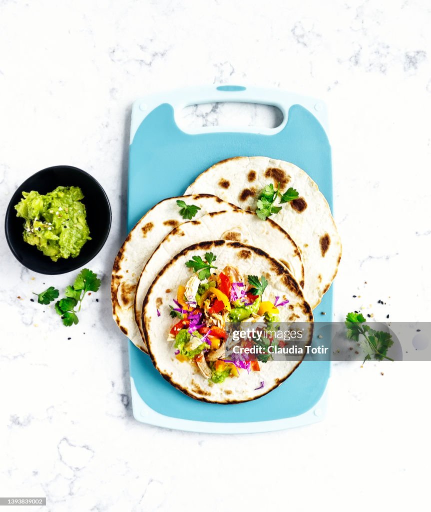 Chicken tacos on cutting board on white, marble background