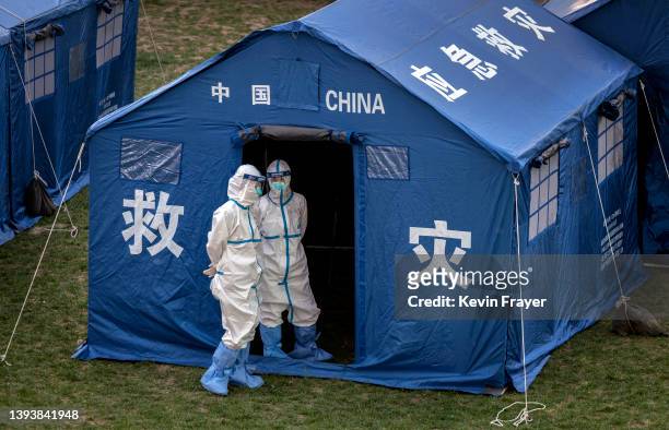 Health workers wear protective suits as they stand outside a tent while waiting to perform nucleic acid tests to detect COVID-19 on local workers at...