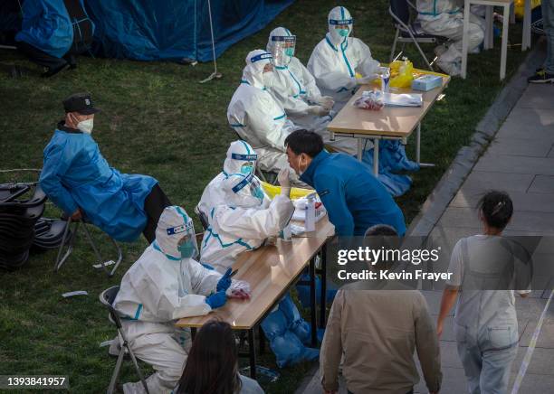 Health workers wear protective suits as employees from local high tech companies are given a nucleic acid tests to detect COVID-19 at a makeshift...