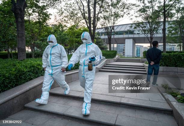 Health workers wear protective suits as they walk and chat during a break from performing nucleic acid tests to detect COVID-19 at a makeshift...