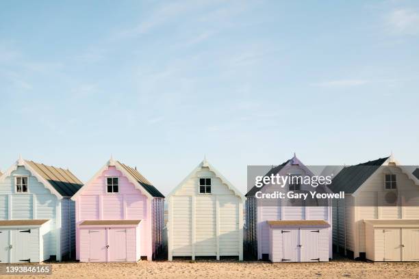 row of colourful beach huts against blue sky - beach hut stock pictures, royalty-free photos & images