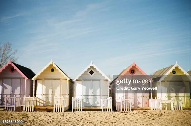 row of colourful beach huts against blue sky - strandhütte stock-fotos und bilder