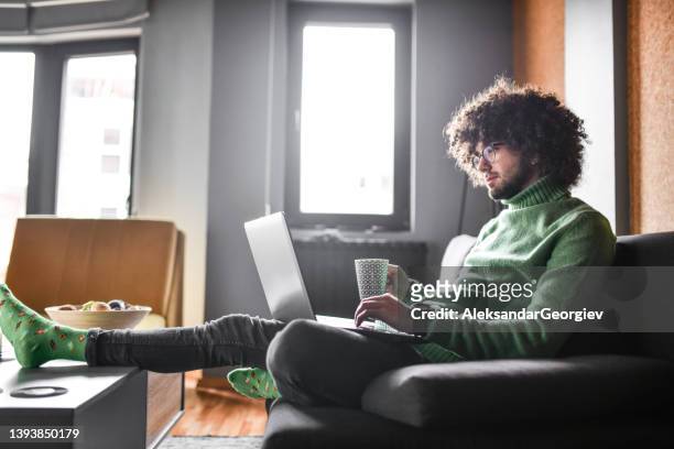 handsome bearded male relaxing and waiting for bank transaction while drinking coffee at home - man and his hoodie imagens e fotografias de stock