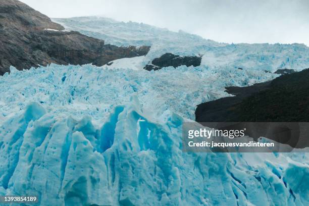 close=up del glaciar perito moreno que fluye desde las montañas - crevasse fotografías e imágenes de stock