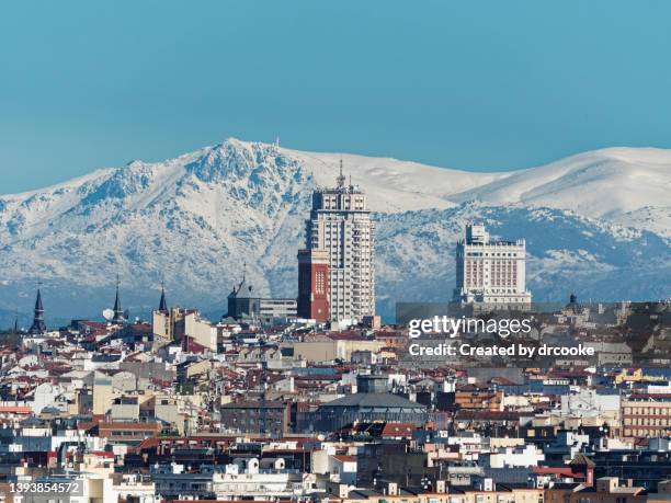 long distance shot of the buildings around plaza de españa with snow covered mountain in the background - madrid snow stock pictures, royalty-free photos & images