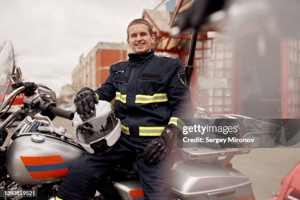 happy fireman with helmet sitting on motorbike - rescue worker foto e immagini stock