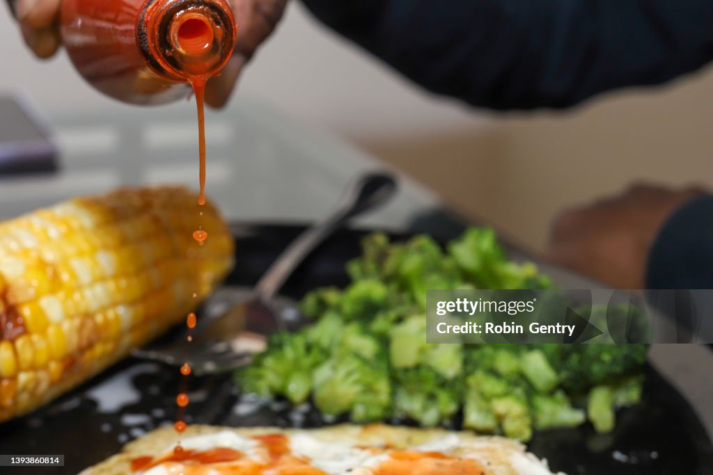 A black African-American man pouring hot sauce on food