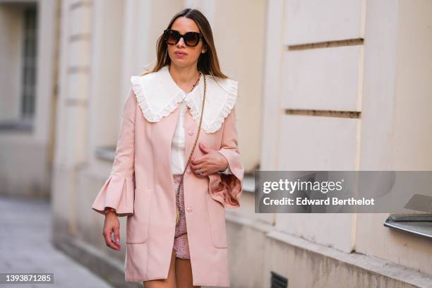 Maria Rosaria Rizzo wears brown sunglasses, a white with lace pattern oversized blouse / shirt from La petite Étoile, a beige shiny leather circle...