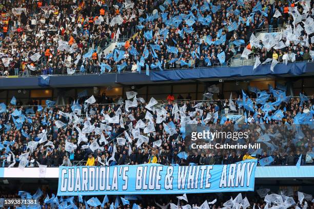 Banner which reads ' Guardiola's Blue & White Army' is seen inside the stadium as Manchester City fans wave flags during the UEFA Champions League...