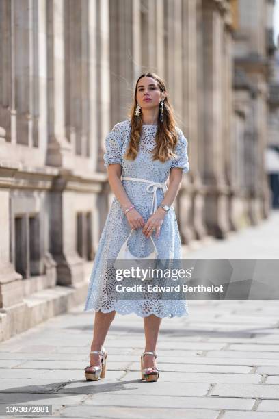 Maria Rosaria Rizzo wears oversized gray blue and white pendant pattern earrings from Rosa Ladisa, a pale blue cut-out lace pattern midi dress with...