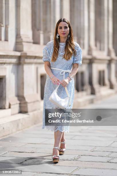 Maria Rosaria Rizzo wears oversized gray blue and white pendant pattern earrings from Rosa Ladisa, a pale blue cut-out lace pattern midi dress with...