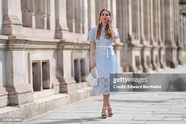 Maria Rosaria Rizzo wears oversized gray blue and white pendant pattern earrings from Rosa Ladisa, a pale blue cut-out lace pattern midi dress with...