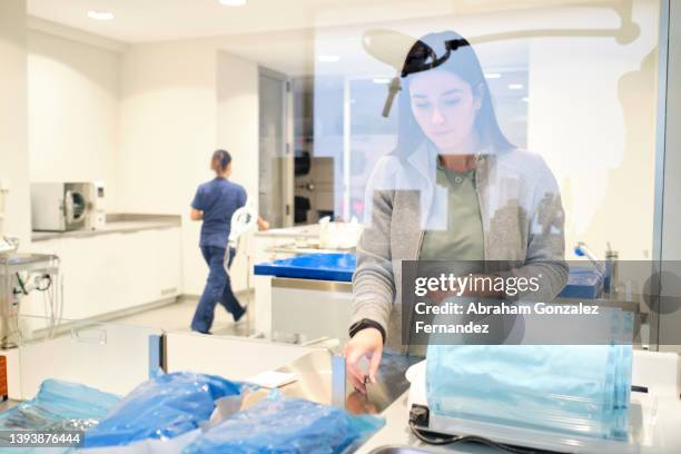 view through glass of a veterinarian preparing surgical instruments for an operation - preparing drug in hospital nurse stock-fotos und bilder