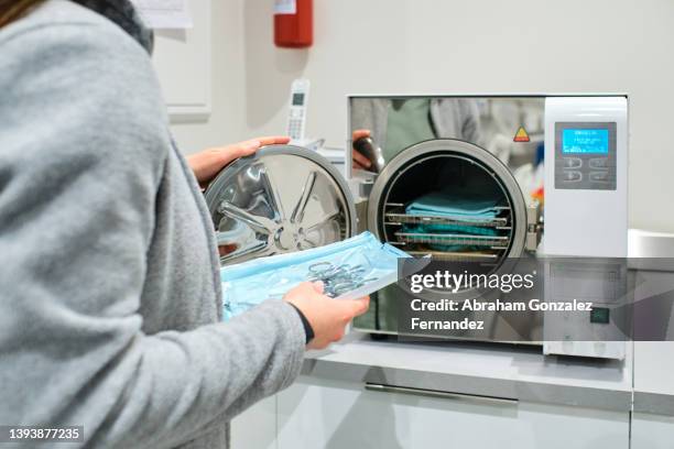 nurse putting dental surgical tools in modern laboratory autoclave sterilizer - sprechstundenhilfe stock-fotos und bilder