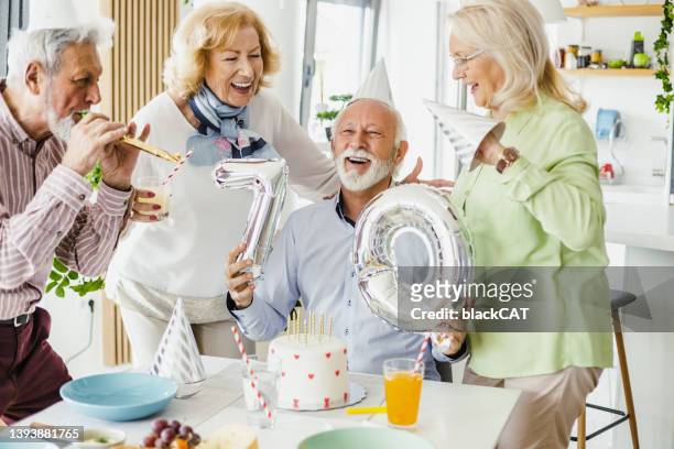 senior man celebrating 70th birthday with friends - ages 65 70 stockfoto's en -beelden