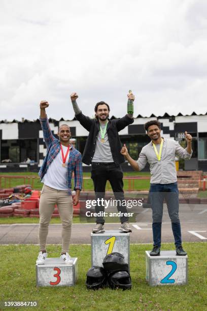 happy men celebrating in the podium after a go-carting race - winners podium people stock pictures, royalty-free photos & images