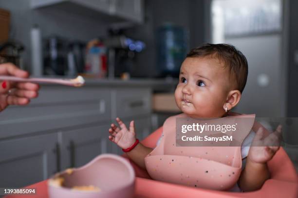 cheerful baby girl eating meal with mother - bright food stock pictures, royalty-free photos & images