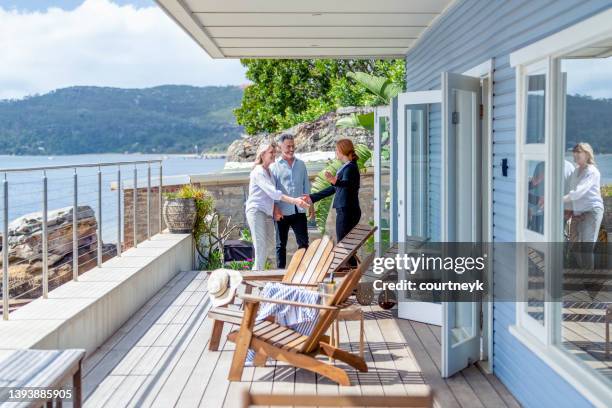 real estate agent showing a mature couple a new house. - bens imóveis imagens e fotografias de stock