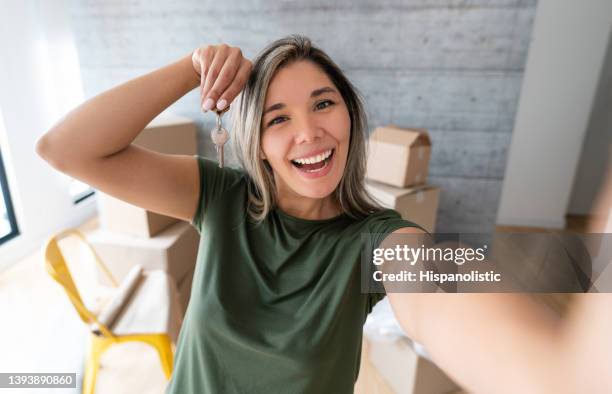 mulher feliz tirando uma selfie segurando as chaves de sua nova casa - house keys - fotografias e filmes do acervo