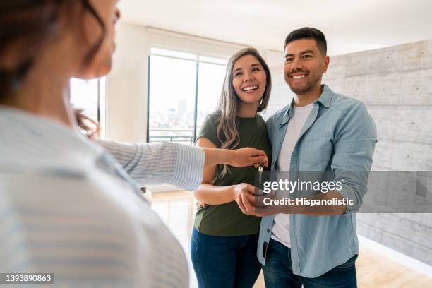 agent immobilier donnant les clés de leur nouvelle maison à un couple heureux - propriétaire immobilier photos et images de collection