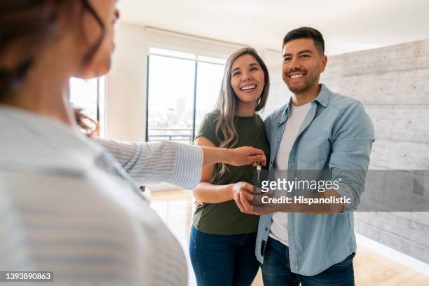 real estate agent giving the keys of their new house to a happy couple - home ownership keys stock pictures, royalty-free photos & images