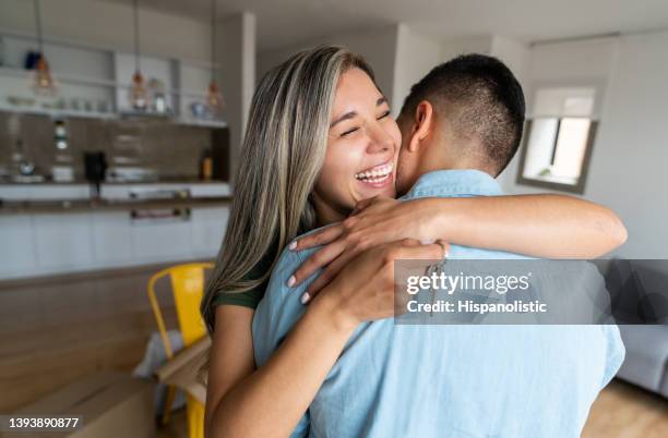 couple achetant une maison et ayant l’air très excité en tenant les clés - mortgage loan photos et images de collection