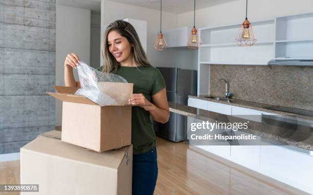 woman moving house and packing in boxes using bubble wrap - handle with care stockfoto's en -beelden