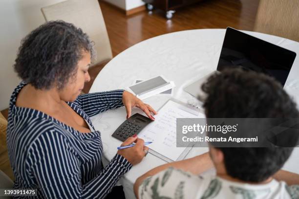 mother and son planning their finances at home - schulden stockfoto's en -beelden